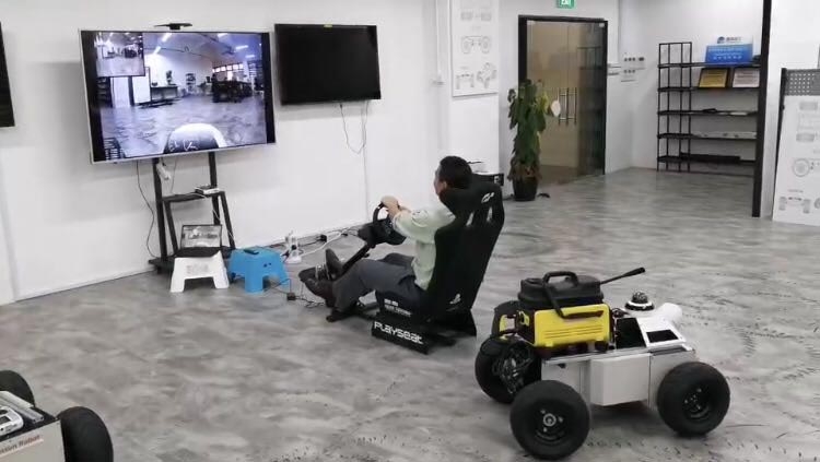 机器人被显示在前景中。操作者在一个大的屏幕，示出了机器人的周围的前就位。操作者控制与方向盘的机器人。