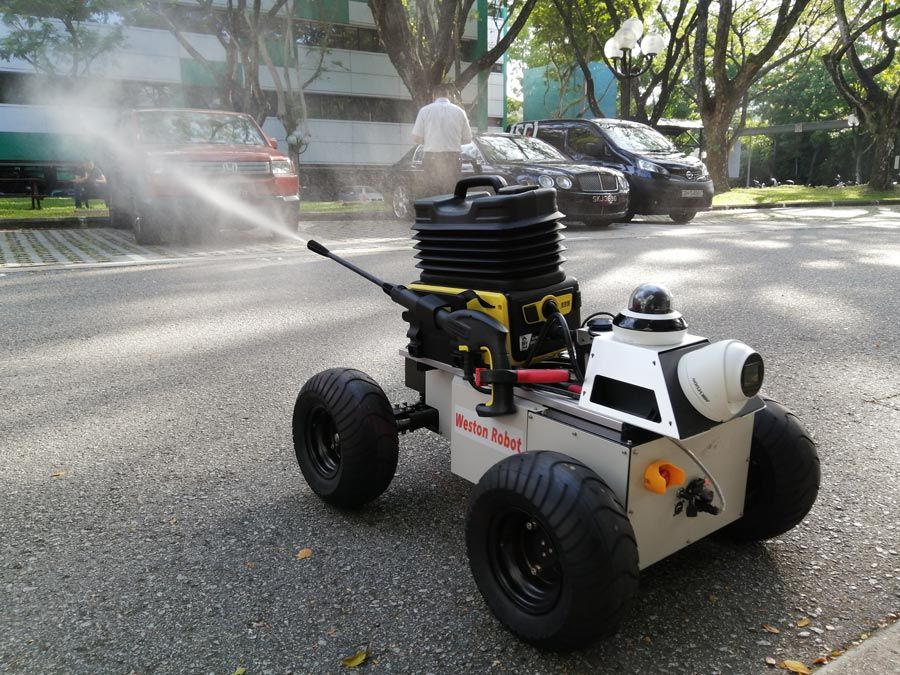 韦斯顿机器人原型在一个平坦的街道,积极外面喷涂。汽车和一个人的背景图像。