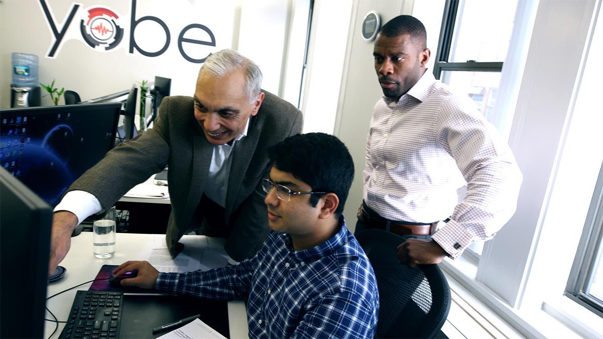 纳瓦布博士和肯·萨顿在波士顿Yobe总部向一名软件开发人员咨询。