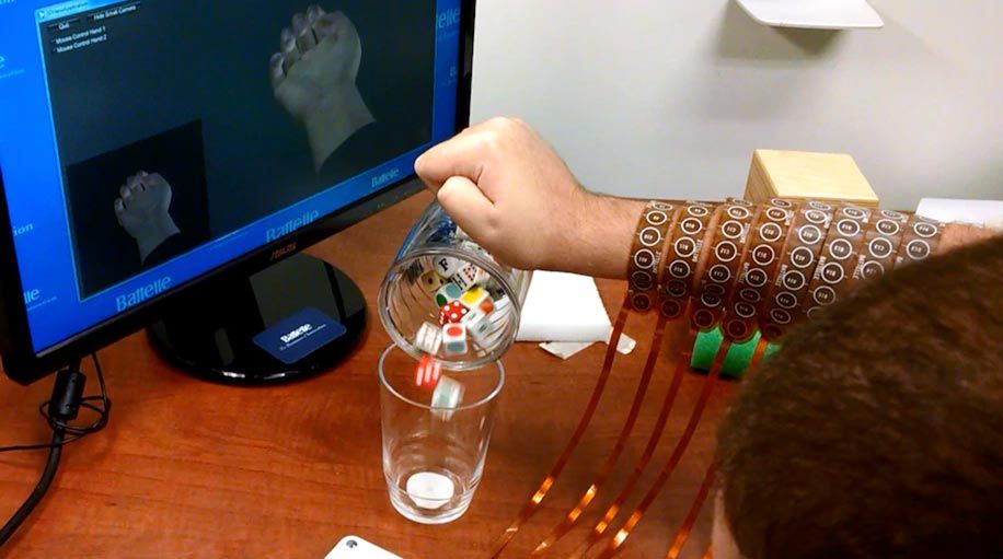 右上角的电脑屏幕上显示了Burkhart的手的化身，他的手(屏幕中间)紧握着杯子。他正把杯子里的冰块倒进杯子里。